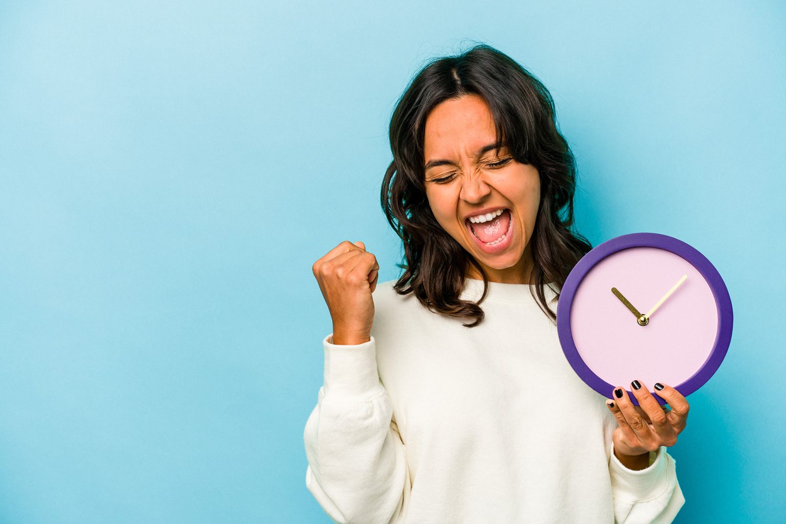 femme qui est contente de gagner du temps. Elle tient un réveil dans la main.