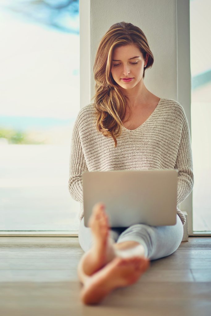 Femme assise par terre créant une affiche depuis son ordinateur portable