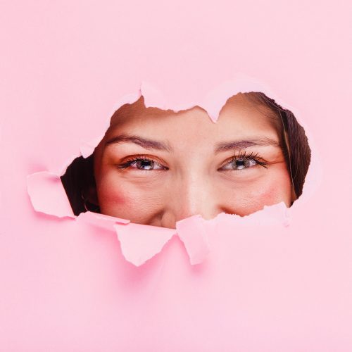 femme qui regarde au travers d'une feuille déchirée